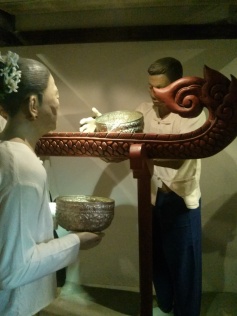 Mannequins demonstrate the special tool used to bathe the Buddha image as an offering